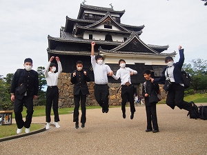 松江城の前でジャンプして記念撮影する生徒たち