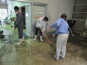 ブラシで床を清掃する生徒たち
