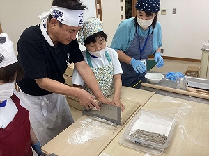小村さんと一緒に包丁で綿を切る生徒